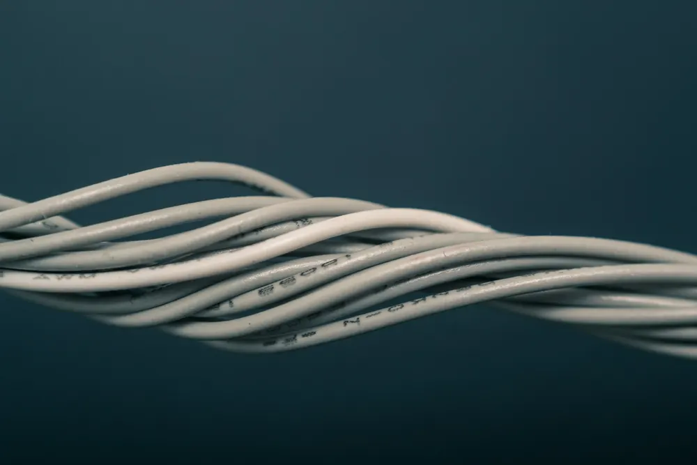 Varios cables eléctricos flexibles grises trenzados sobre fondo azul oscuro